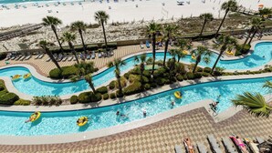 A pool area with multiple swimming pools, lounge chairs, and palm trees. - Phoenix West 3 BR ~ LOW FLOOR!!! (Orange Beach)