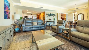 A spacious living room with a sofa, armchairs, a coffee table, and a dining area with chairs. - Phoenix West 3 BR ~ LOW FLOOR!!! (Orange Beach)