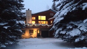 A snow-covered house with a chimney, a porch with lights, and snow-laden trees. - 260+ 10★ Reviews!  Between Vail & Beaver Creek Hot Tub/Fire Table/Ski/Hike/ Golf (Vail)