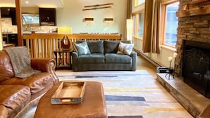 A cozy living room with a fireplace, leather sofas, a wooden coffee table, and a kitchen area in the background. - 260+ 10★ Reviews!  Between Vail & Beaver Creek Hot Tub/Fire Table/Ski/Hike/ Golf (Vail)