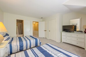 Un dormitorio con dos camas, televisor, cómoda y vestidor.