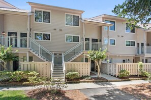 A multi-story residential building with a central staircase, balconies, and a gated entrance.