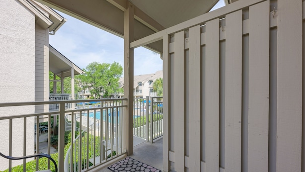 Ein Balkon mit Blick auf einen Swimmingpool und eine überdachte Terrasse.