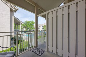 Een balkon met uitzicht op een zwembad en een overdekt terras.