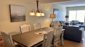 Ein Essbereich mit Holztisch und -stühlen, einer Chandelüster und einem Gemälde an der Wand.
