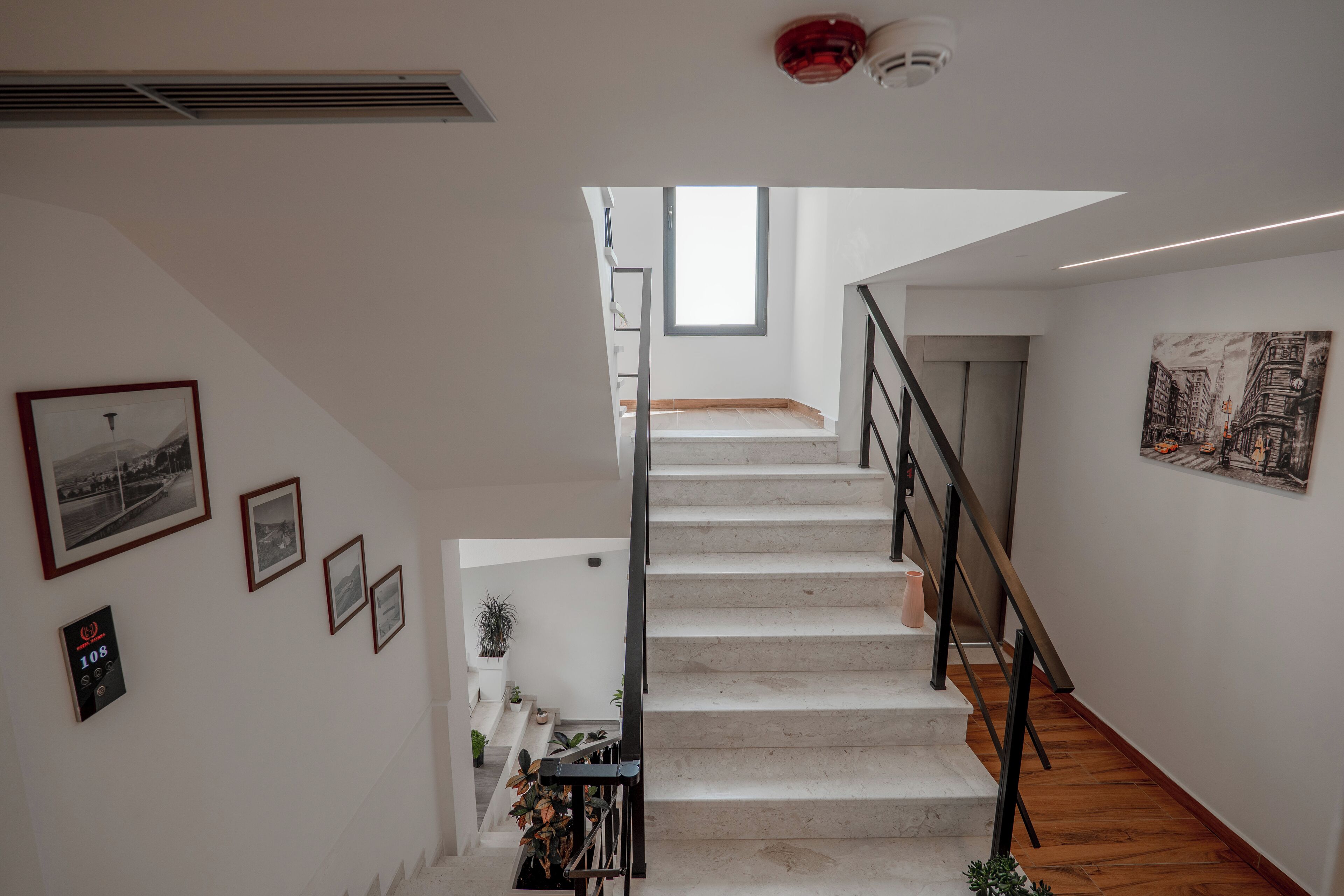 A staircase with a modern design, white walls, and a small window at the top.