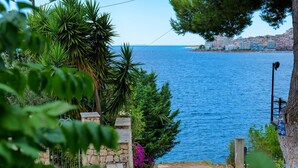 A coastal view with a stone staircase leading to a beach, surrounded by greenery and a clear blue sea. - Hotel Havana (Sarandë)