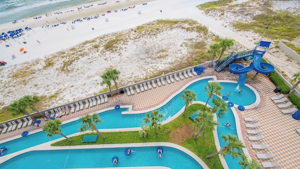Un resort con piscina, sillones de descanso y playa.