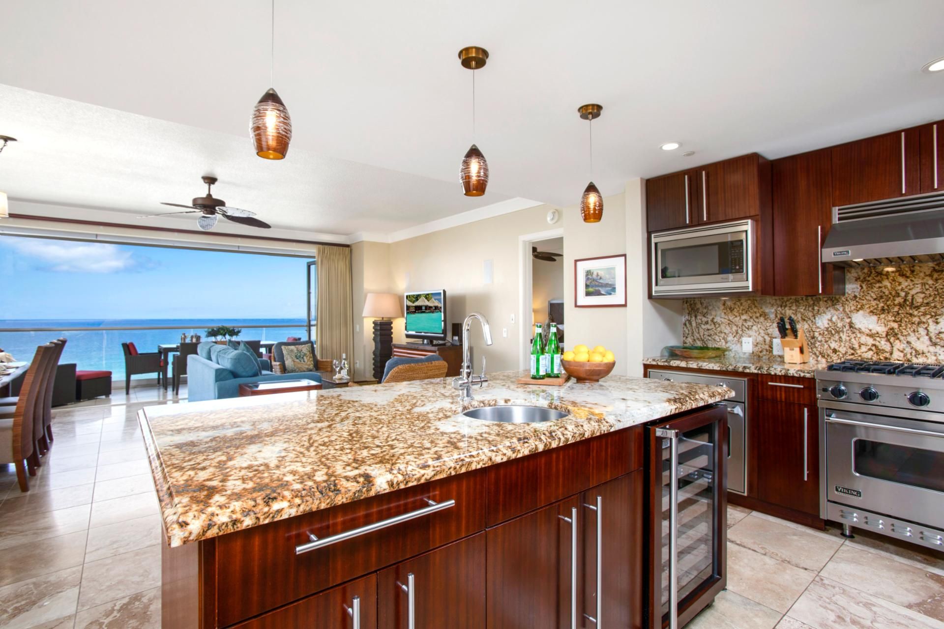 A modern kitchen with granite countertops, stainless steel appliances, and a view of the ocean.