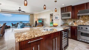 A modern kitchen with granite countertops, stainless steel appliances, and a large island. - Honua Kai | Ocean View 3 BR Sleeps 8 | Car Incl. w/ 6+ Nights | HKH-925 by KBM (Lahaina)