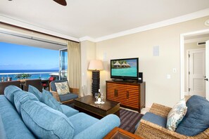 Ein Wohnzimmer mit einer Couch, einem Couchtisch, einem Fernseher und Blick auf den Ozean.