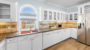 A modern kitchen with white cabinetry, a granite countertop, a stainless steel refrigerator, and a window with a view. - Heavenly Sunset...A House With Amazing Views And Just Steps From The Beach (Surfside Beach)
