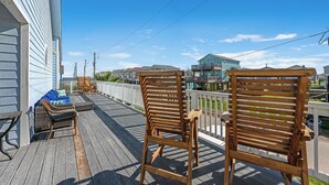 A wooden deck with two wicker chairs and a grill, overlooking a residential area with houses and a clear sky. - Heavenly Sunset...A House With Amazing Views And Just Steps From The Beach (Surfside Beach)