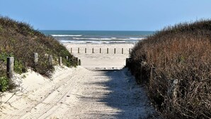 A sandy beach path leading to the ocean, flanked by vegetation and wooden posts. - LP11 Ocean View from Deck, Boardwalk, Golf Cart Access (Port Aransas)