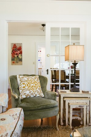 Un salon chaleureux avec un fauteuil vert, un coussin à motifs, une petite table en bois et une lampe.
