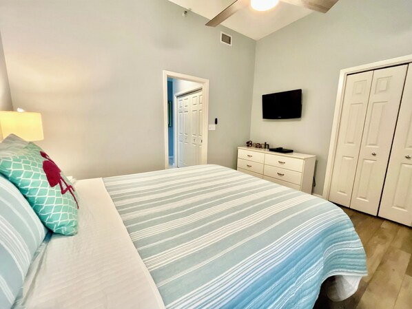 A bedroom with a bed, a dresser, a television, and a closet.
