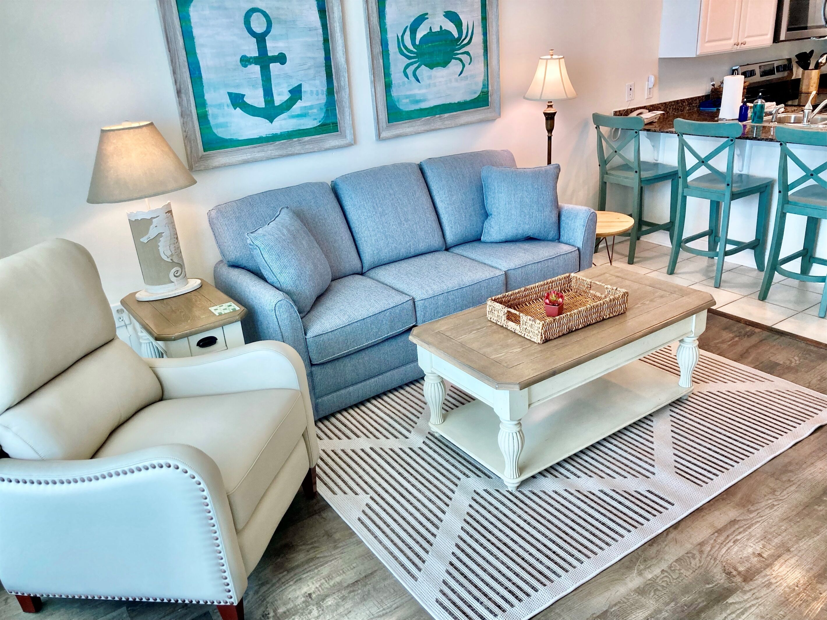 A living room with a light blue sofa, a white armchair, a wooden coffee table, and a patterned rug.