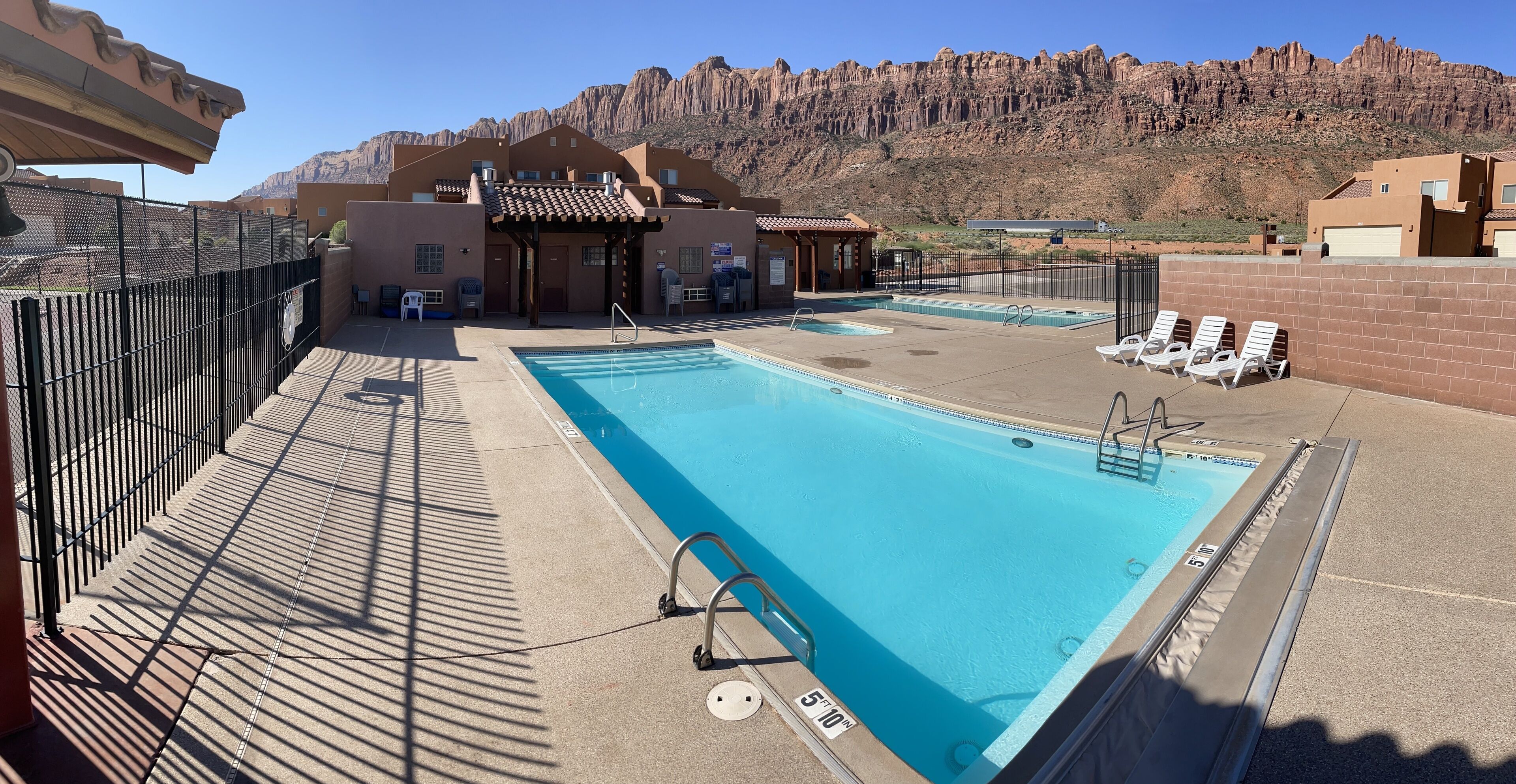Piscina no terraço com vista para uma paisagem montanhosa, rodeada por edifícios com design moderno.