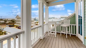 A wooden deck with white railings, a staircase, and a view of neighboring houses. - Luxe Palmilla Beach Resort house with pool, dining & private golf cart (Port Aransas)