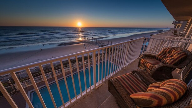 A balcony with a pool, overlooking a beach at sunset. - Direct Oceanfront - Heated Pool & Hot Tub (Daytona Beach Shores)