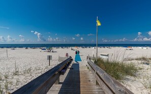 Walk along the boardwalk to a sandy beach area with umbrellas and lounge chairs.