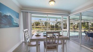 A dining area with a view of a swimming pool and palm trees. - Canal Escape, Boat Rental, Hot Tub, Fishing (Cape Coral)