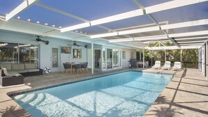 A covered swimming pool with a patio area, including a dining table and chairs, and a ceiling fan. - Canal Escape, Boat Rental, Hot Tub, Fishing (Cape Coral)