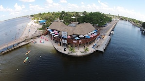 A waterfront restaurant with outdoor seating and a thatched roof. - Canal Escape, Boat Rental, Hot Tub, Fishing (Cape Coral)