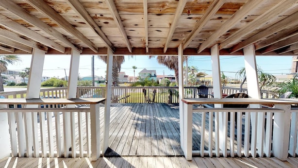 A wooden deck with white railings, leading to a covered area with a wooden ceiling.