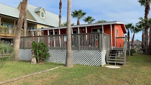 A beachfront property with a red building, a wooden deck, and palm trees.