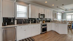 Una cocina moderna con armarios blancos, electrodomésticos de acero inoxidable y una isla grande con asientos.
