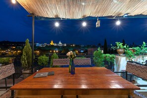 An outdoor dining area with a wooden table, chairs, and a patterned table runner.