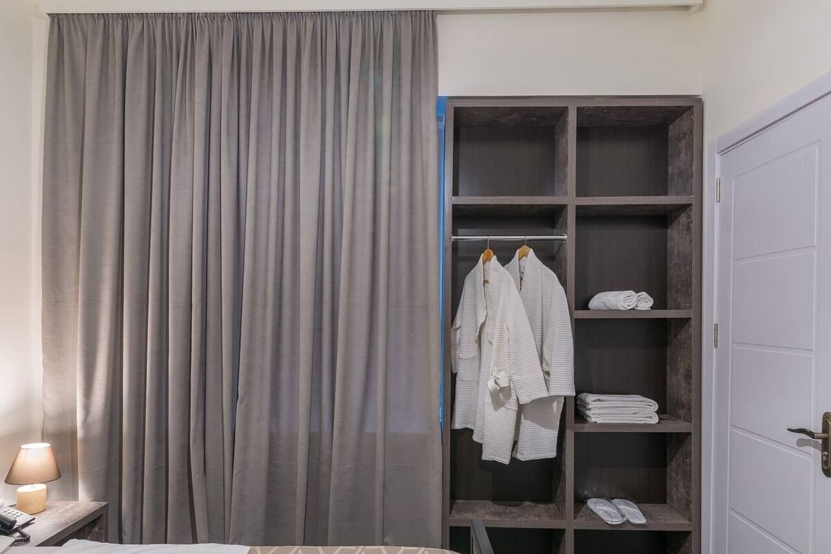 A hotel room with a bed, a wardrobe, and a small seating area.
