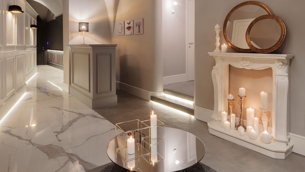 A hallway with a white fireplace, lit candles, and a round mirror on the mantel. - Quattro Canti Suites (Catania)