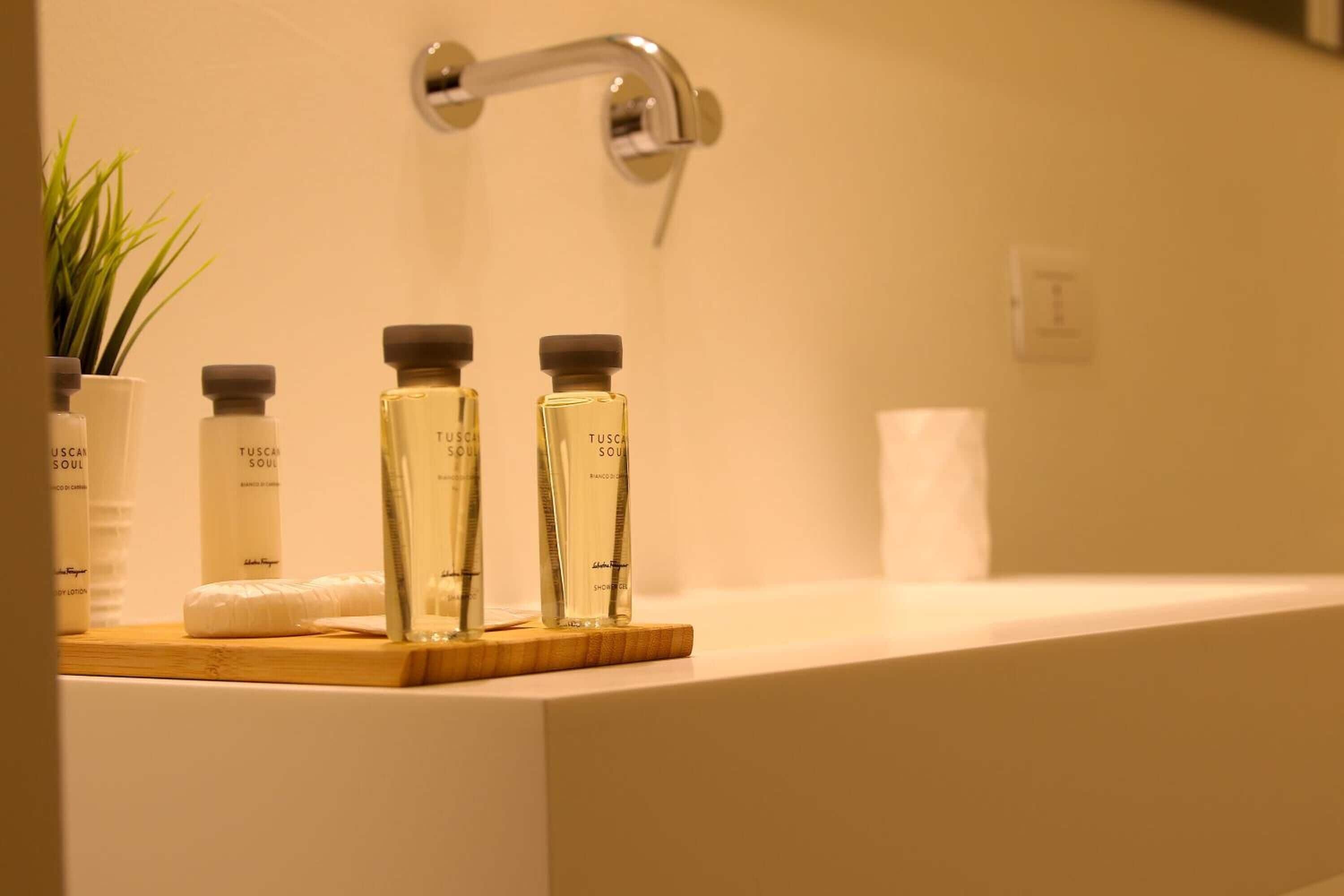 A bathroom with a white sink, two Tuscan Soul scented bottles, and a wooden tray.