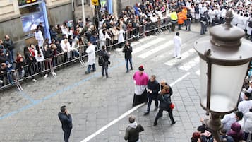A crowded urban street scene with people standing and walking.