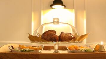 Un tavolo per buffet con cupola in vetro, una candela e diversi piatti contenenti carne e verdure.