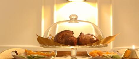Una mesa de bufé con una cubierta de vidrio, una vela y diversos platos que incluyen carne y verduras.