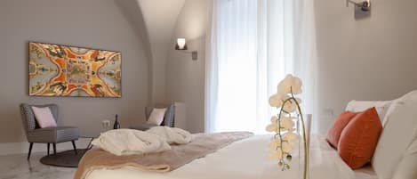A modern hotel room with a large bed, a seating area with a chair and table, a decorative ceiling mural, and a large window with curtains.