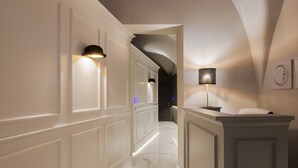 A hallway with white wainscoting, a marble floor, and wall-mounted lighting fixtures. - Quattro Canti Suites (Catania)