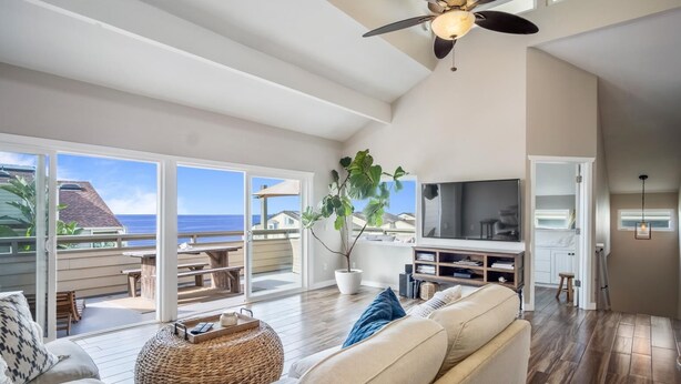 A spacious living area with a large sofa, a television, and a dining area with a view of the ocean. - Gorgeous Ocean View Twinhome w/AC! (Encinitas)