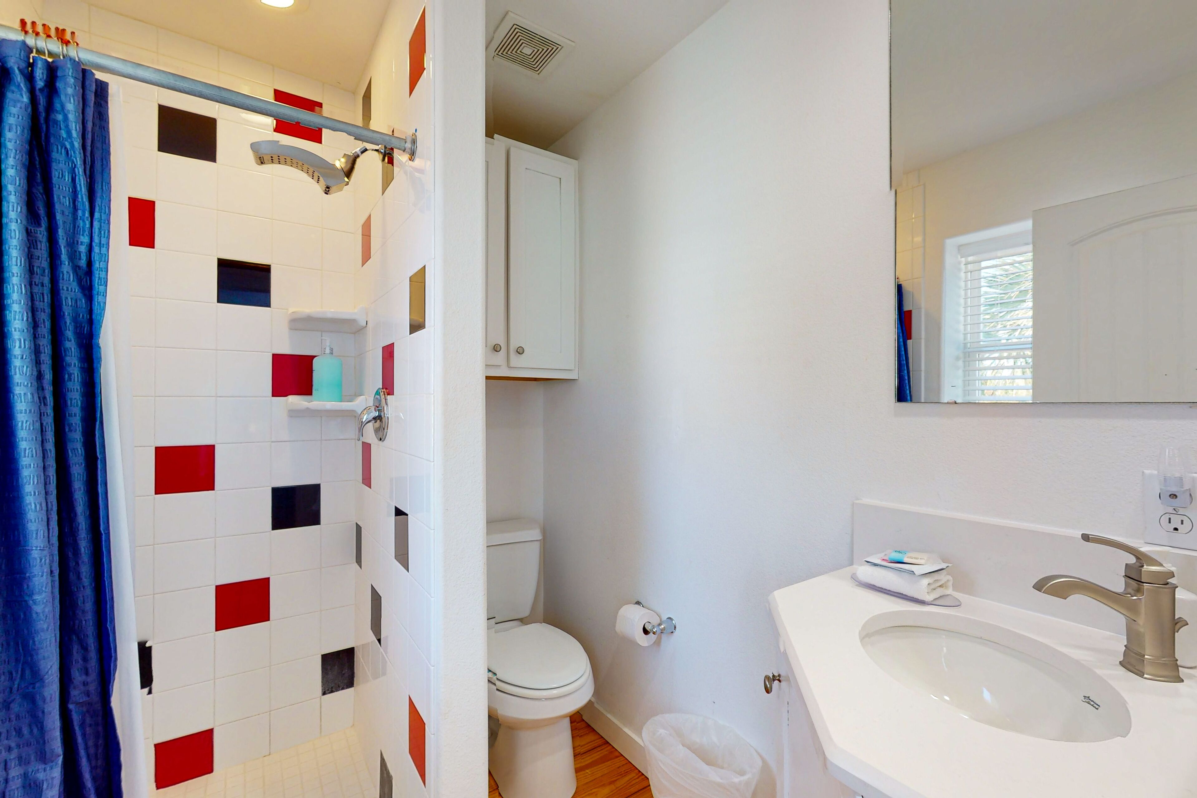 Un baño con ducha, inodoro, lavabo y espejo.