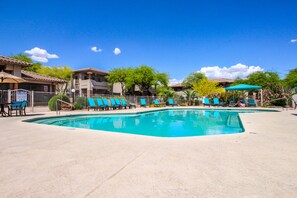 Relax by the pool surrounded by lush greenery and comfortable lounge chairs.