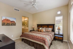 Relax in this serene bedroom with a large bed, nightstand, and ceiling fan.