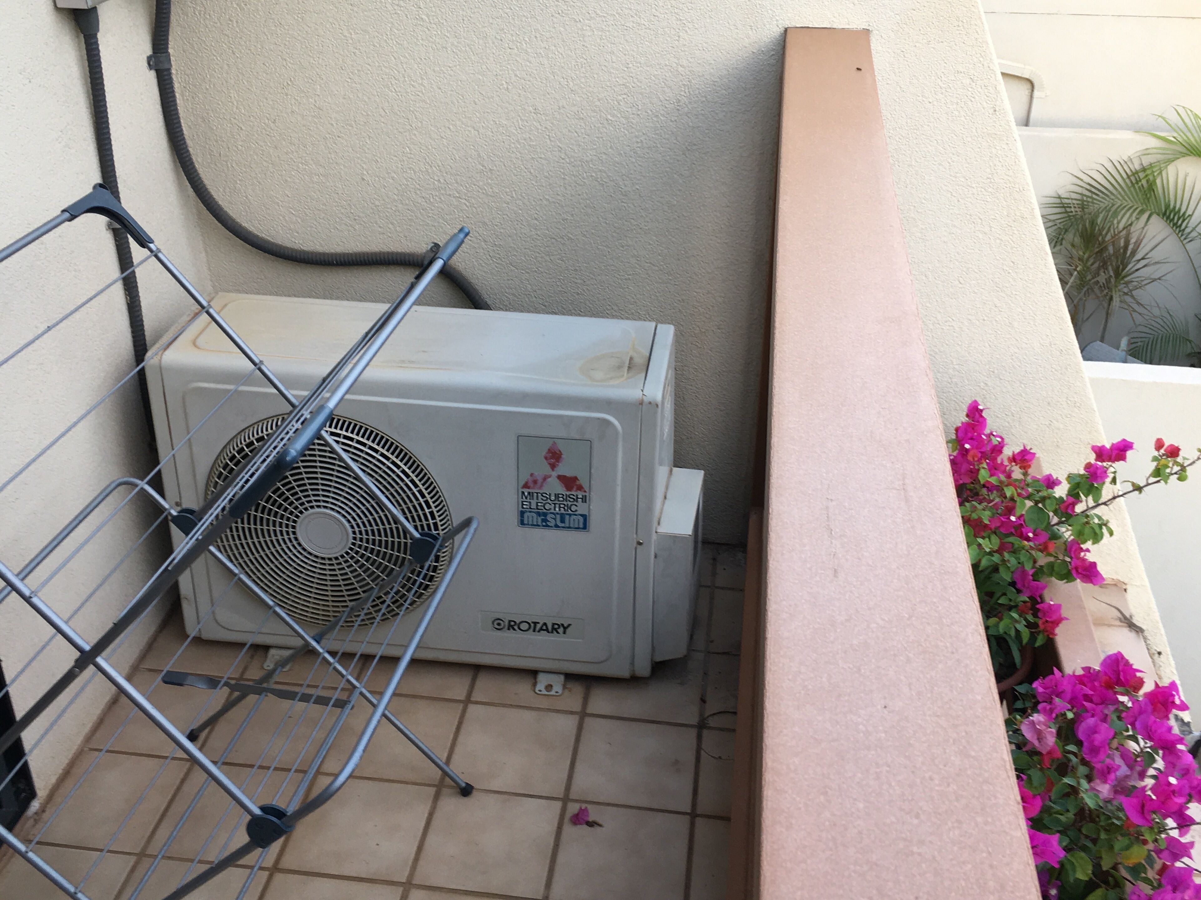 Unitat de climatització amb el distintiu Mitsubishi, un ventilador i una prestatgeria metàl·lica.