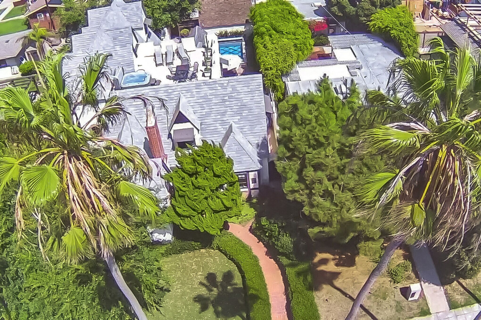 An aerial view of a residential area with houses, a swimming pool, and palm trees.