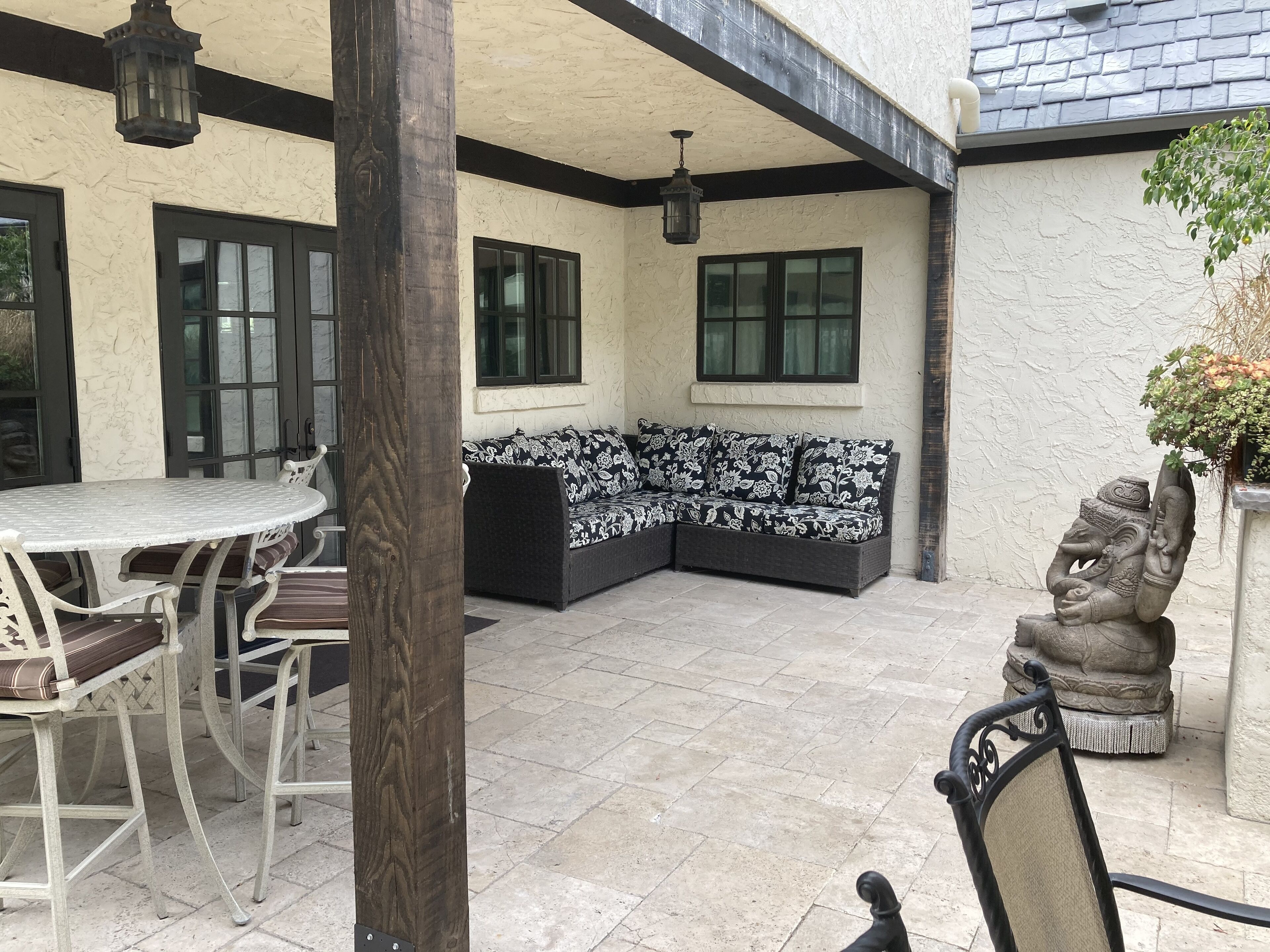 A patio area with a round table and chairs, a black and white patterned sofa, and a stone elephant statue.