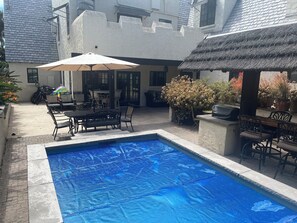 Relax by the pool surrounded by lush greenery and comfortable outdoor furniture.
