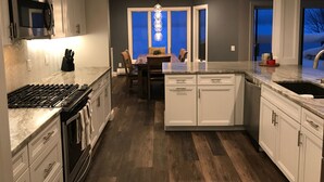 Uma cozinha moderna com armários brancos, forno embutido e um espaço de refeições com parede azul.