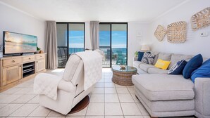 A modern living room with a sofa, a chair, a TV, and a balcony with a view.